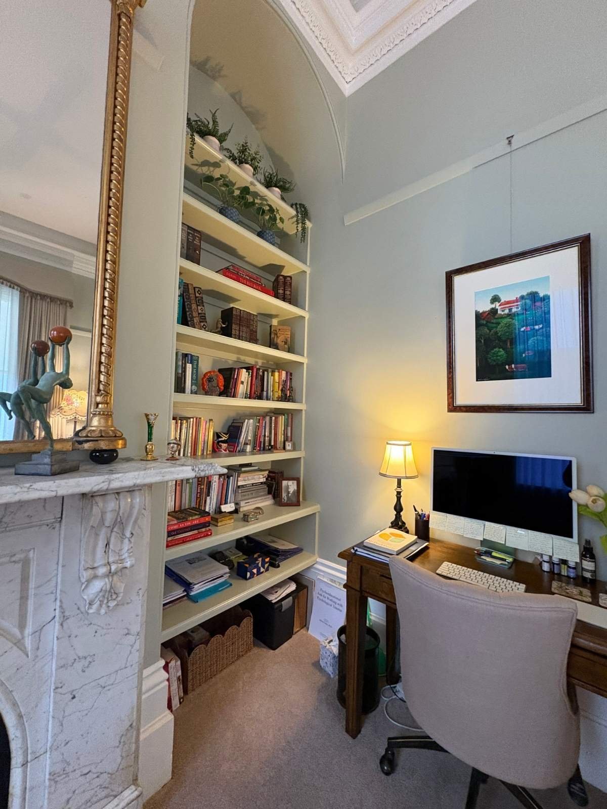 Home office set beside a marble fireplace and full-height built-in bookshelves in the library of the Barkly St heritage home in Bendigo.