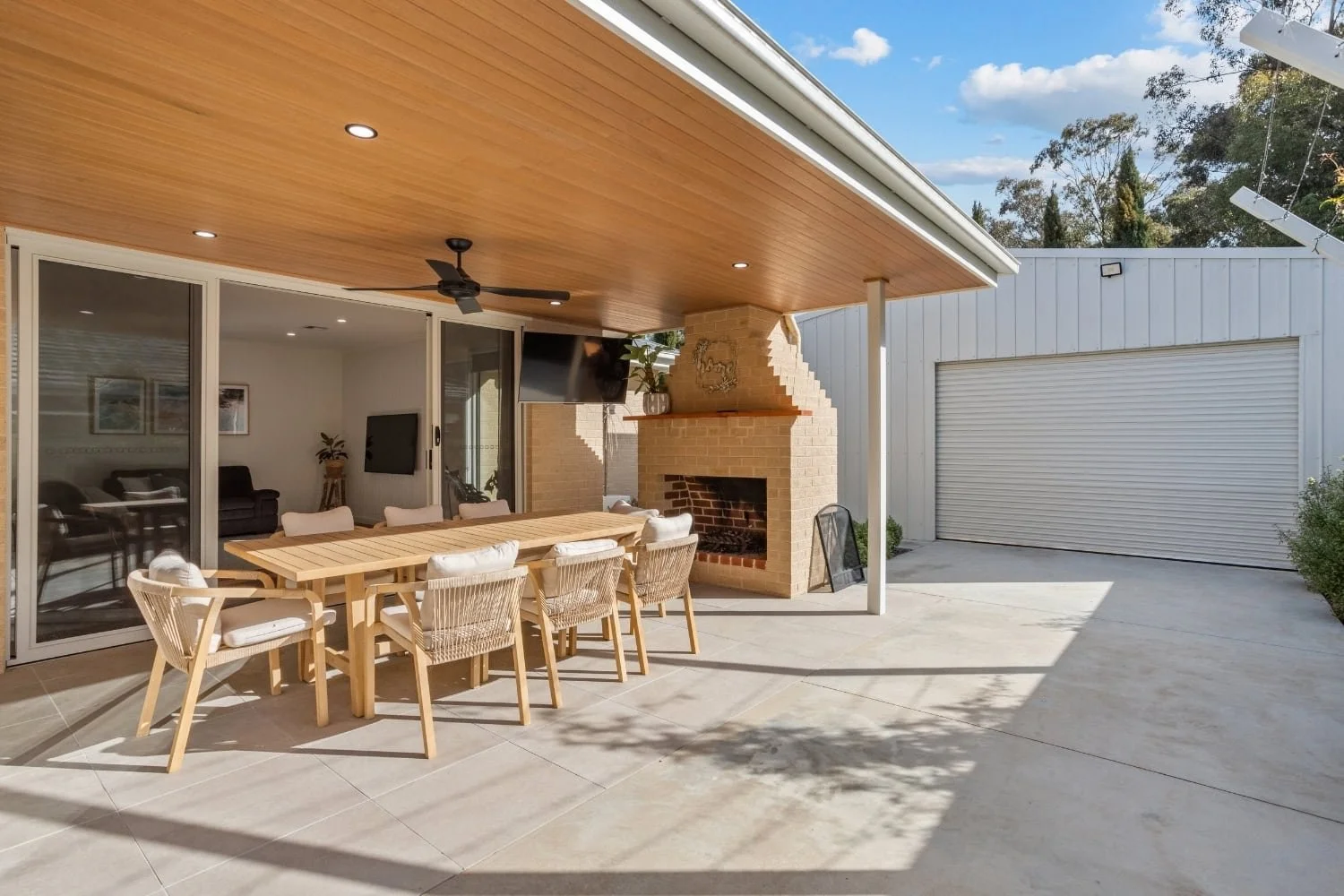 Covered alfresco area with outdoor brick fireplace and dining setting at Marnie Road, Bendigo, by AMW Builders.
