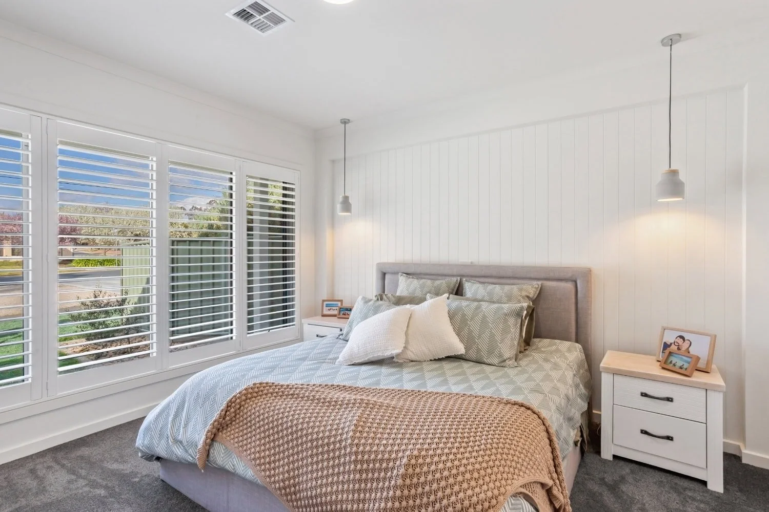 Master bedroom with plantation shutters, feature wall, and pendant lighting at Marnie Road, Bendigo, by AMW Builders.