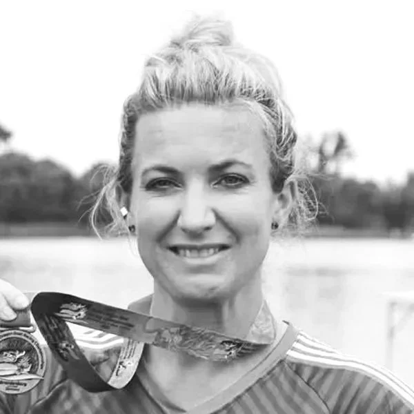 A smiling woman with long hair outdoors, wearing a flower lei.