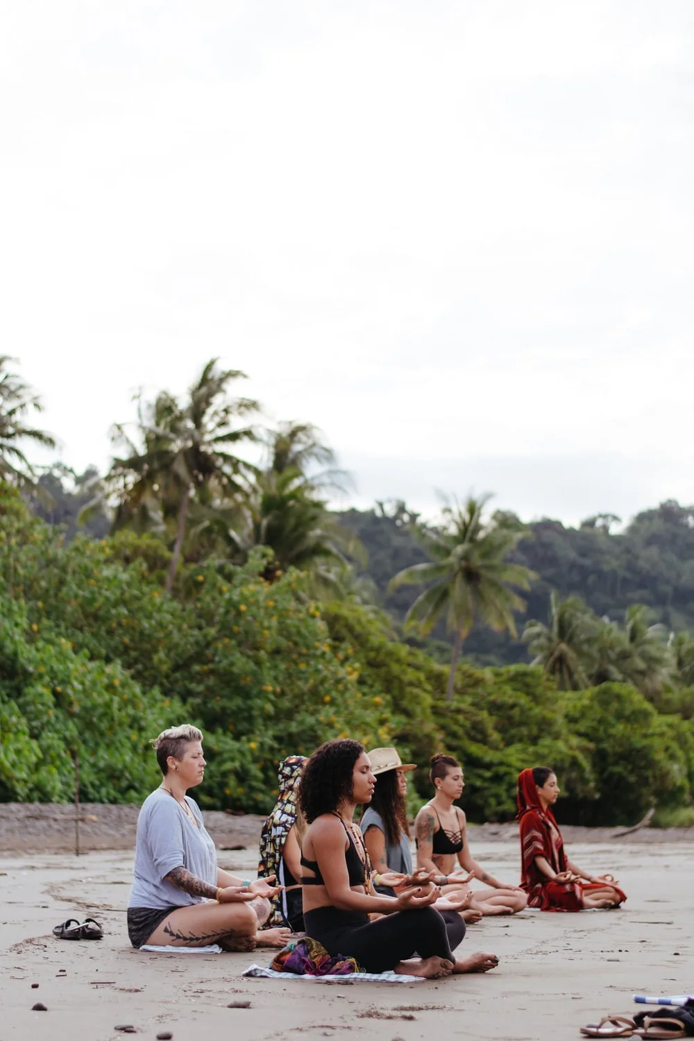 A small group meditating on the beach at Dominical under palm trees