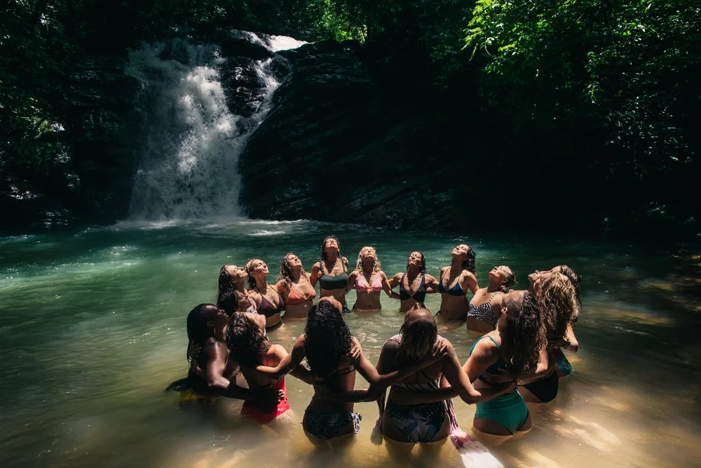 Retreat guests sitting in a circle in a waterfall pool