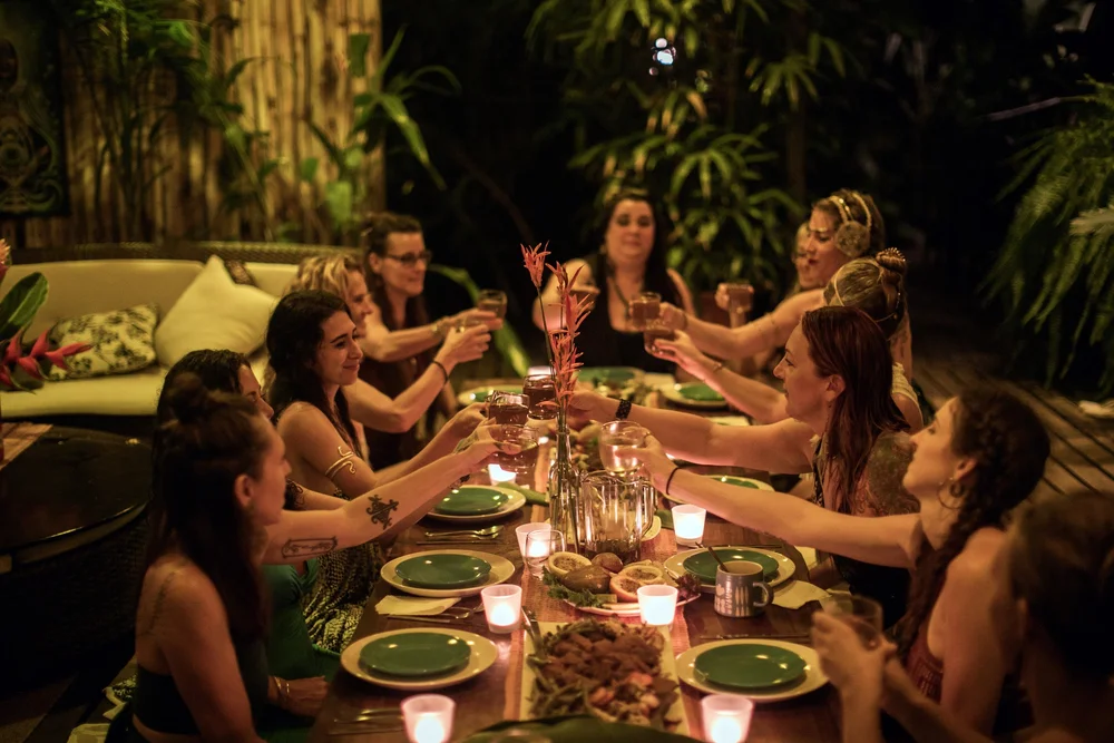 Retreat guests laughing around a candlelit dinner table