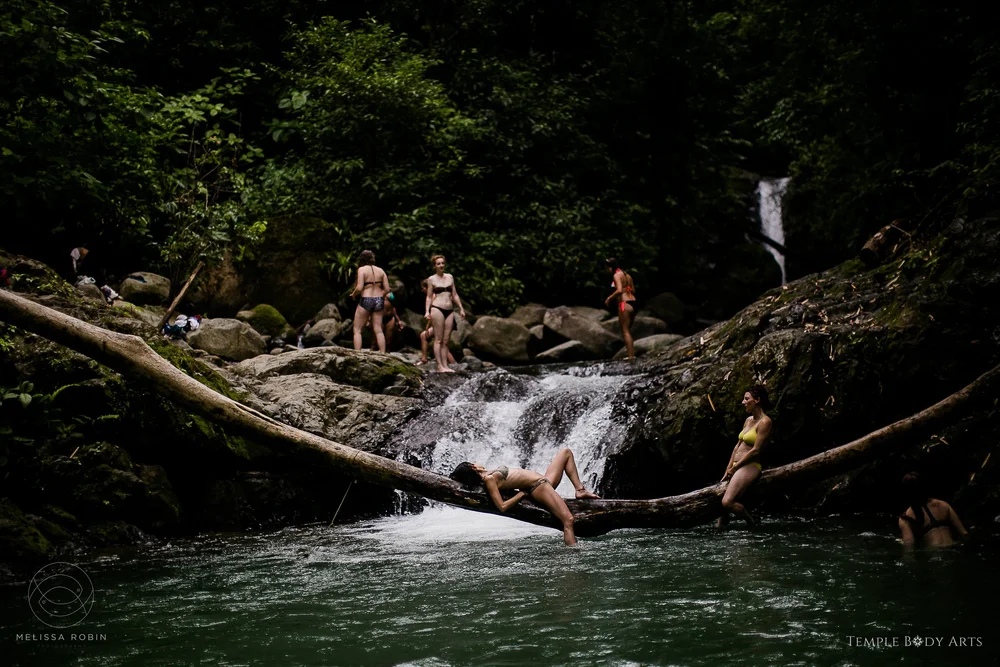 Guests sunbathing on a log over a jungle river