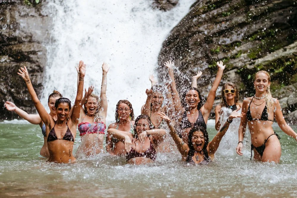 Retreat guests cheering in the pool under a jungle waterfall