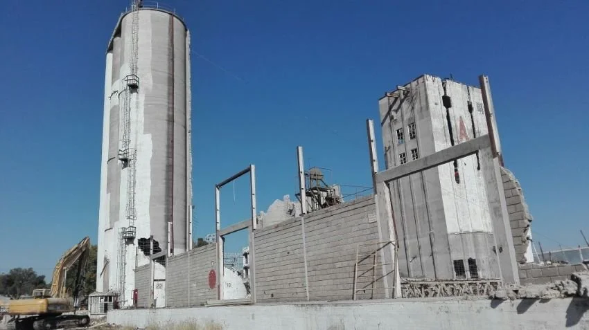 Edificio en ruinas con muros dañados y maquinaria de construcción en primer plano