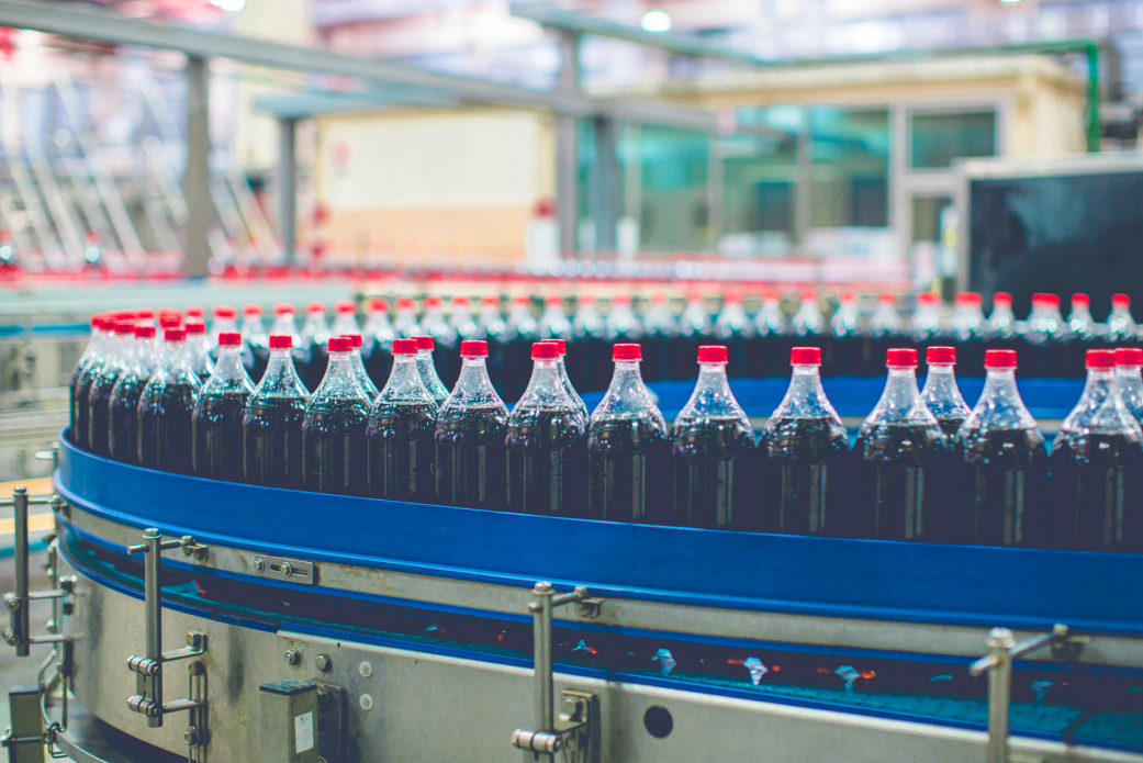 Bottles of soda on a conveyor belt in a factory.