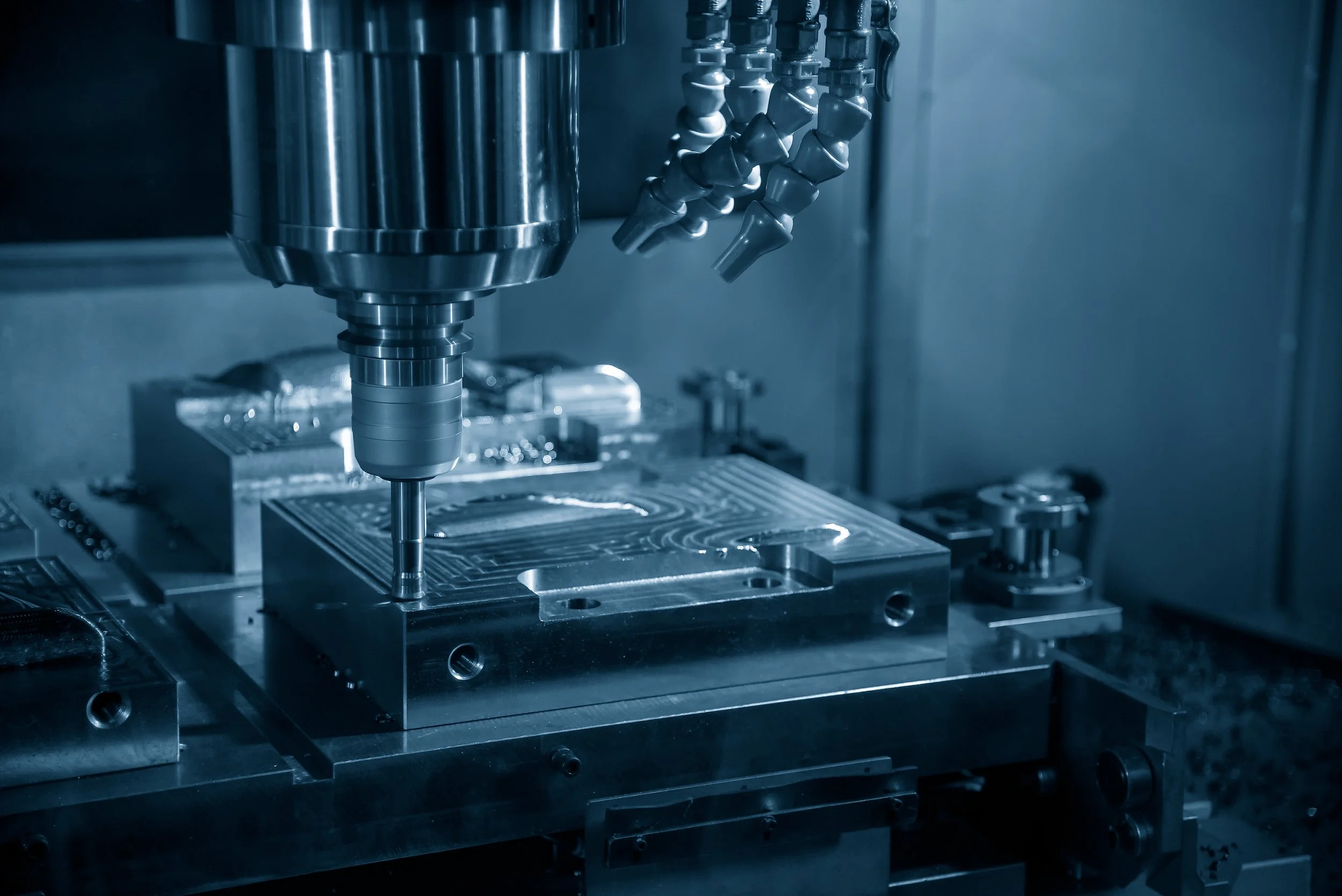 Close-up of a CNC machine drilling into a metal surface in a manufacturing facility.