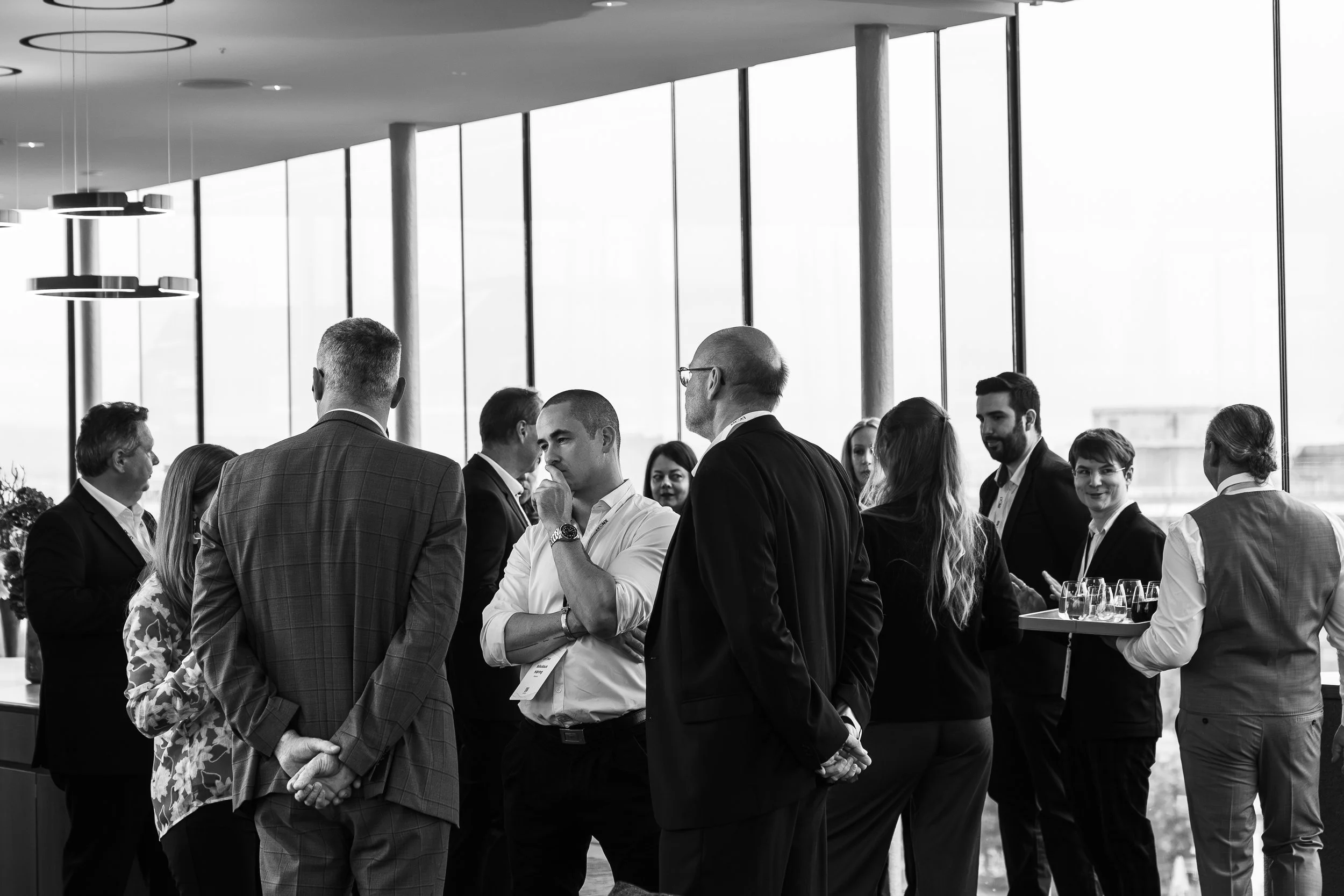 Conference photography  Business professionals at a networking event in a modern conference room with large windows.