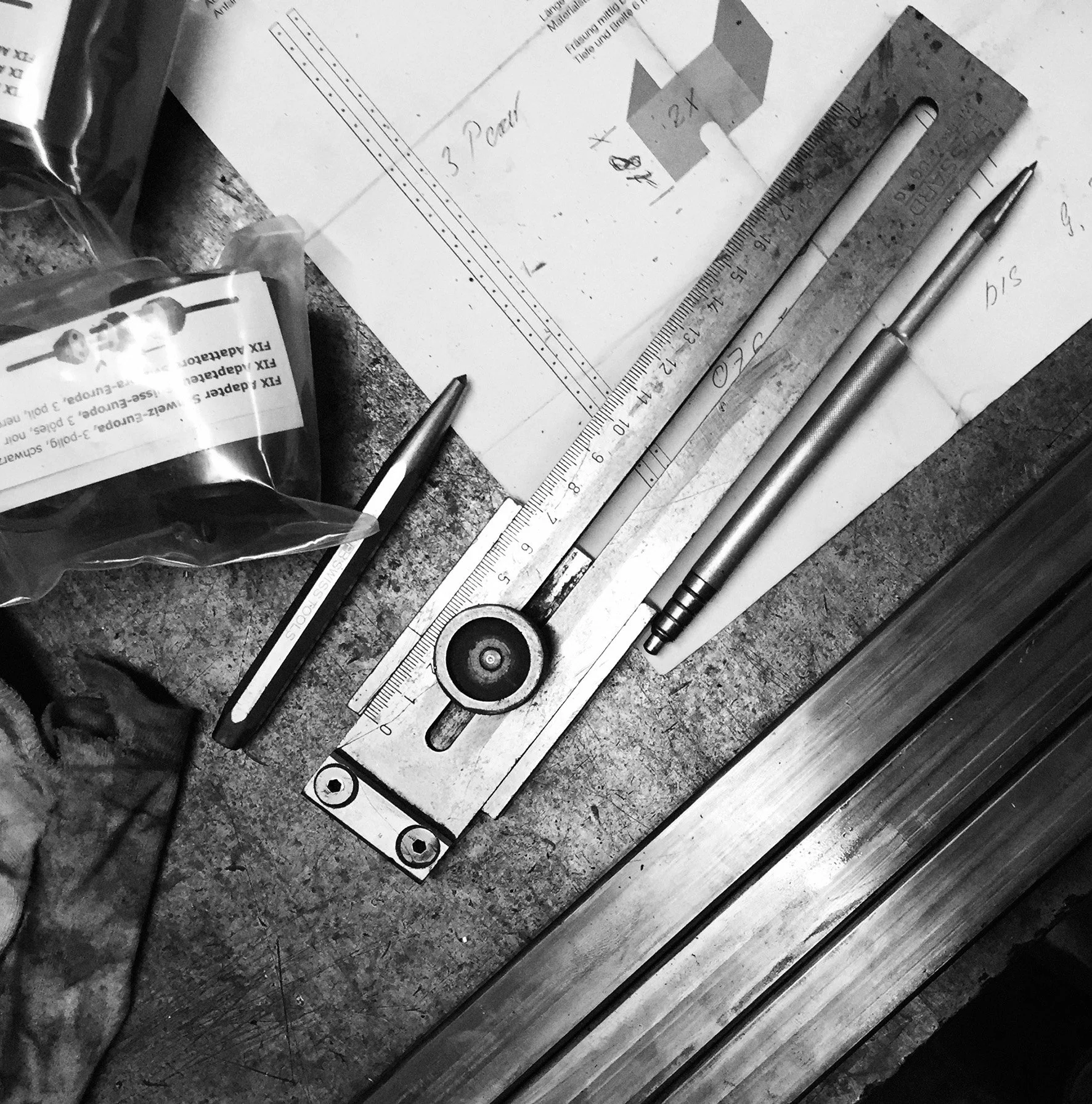 Büro- oder Werkstattarbeitsplatz mit Metalllineal, Kugelschreiber, Bleistift, Papier mit technischen Zeichnungen und Verpackung mit Schrauben.