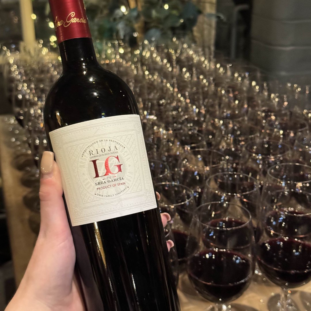 Someone holding a bottle of Reserva wine, with lots of glasses of poured wine in the background
