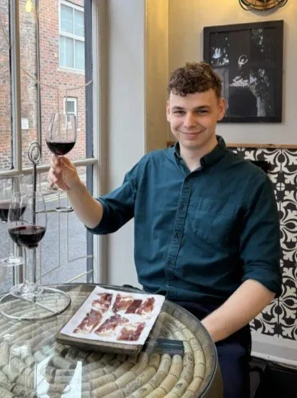 Man holding up Rioja Wine next to rioja Flight and board of Jamon