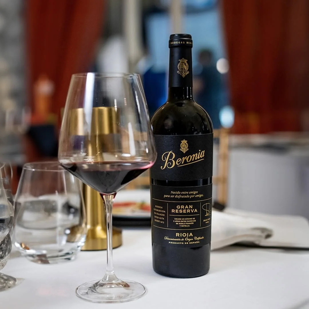 A large glass of Gran Reserva wine with the bottle placed slightly behind on top of a table