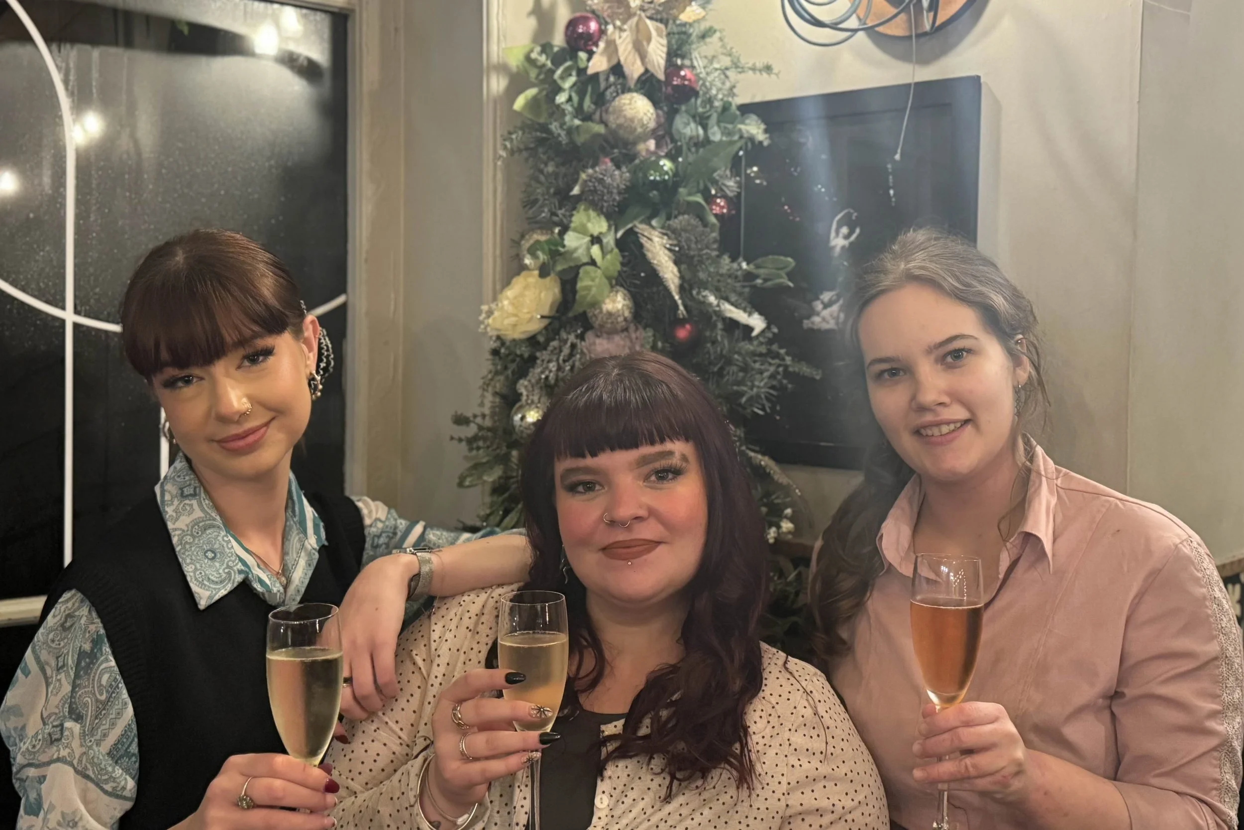 Three team members with a glass of Cava cheersing for New year 
