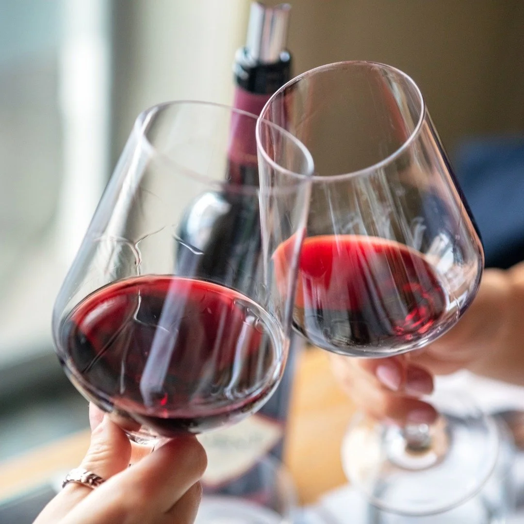 Two people cheersing glasses of red wine