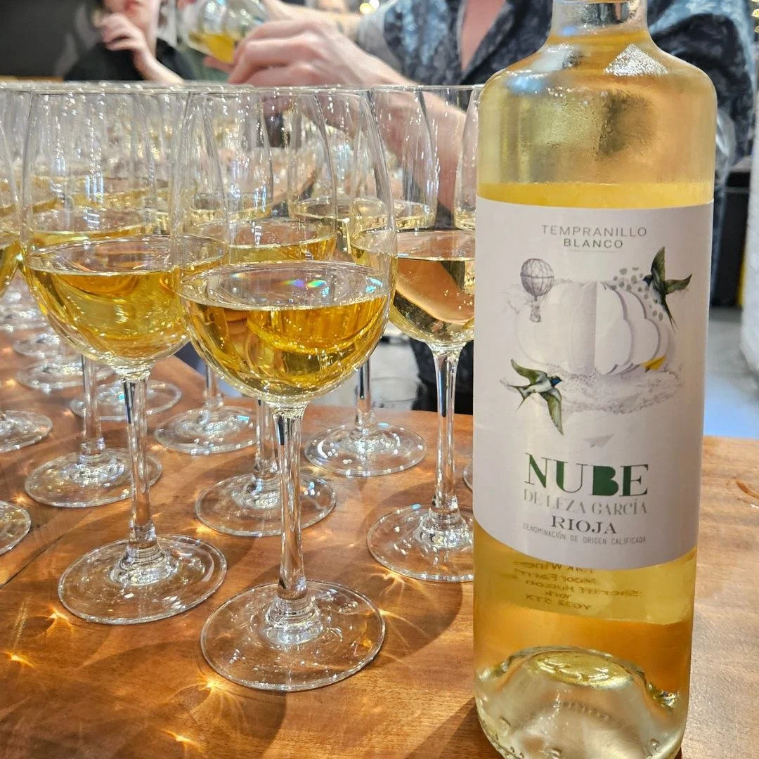 A bottle of Nube White Rioja, with several poured glasses to the left of the bottle