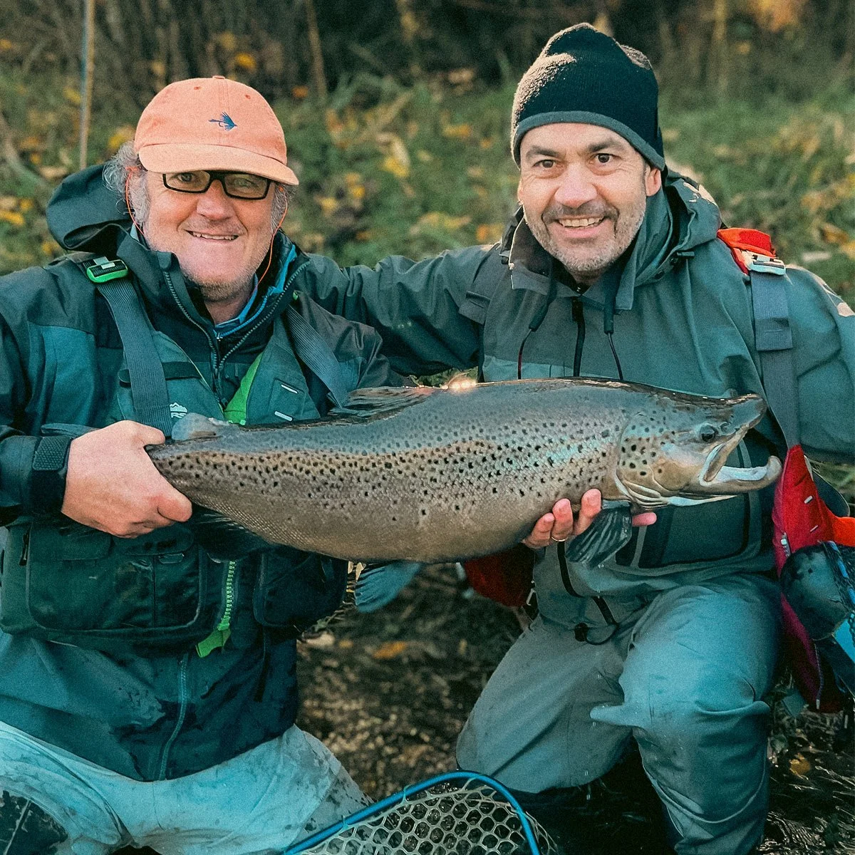 Two happy anglers holding a massive trophy wild brown trout on a guided fly fishing trip in Northern Patagonia, Chile