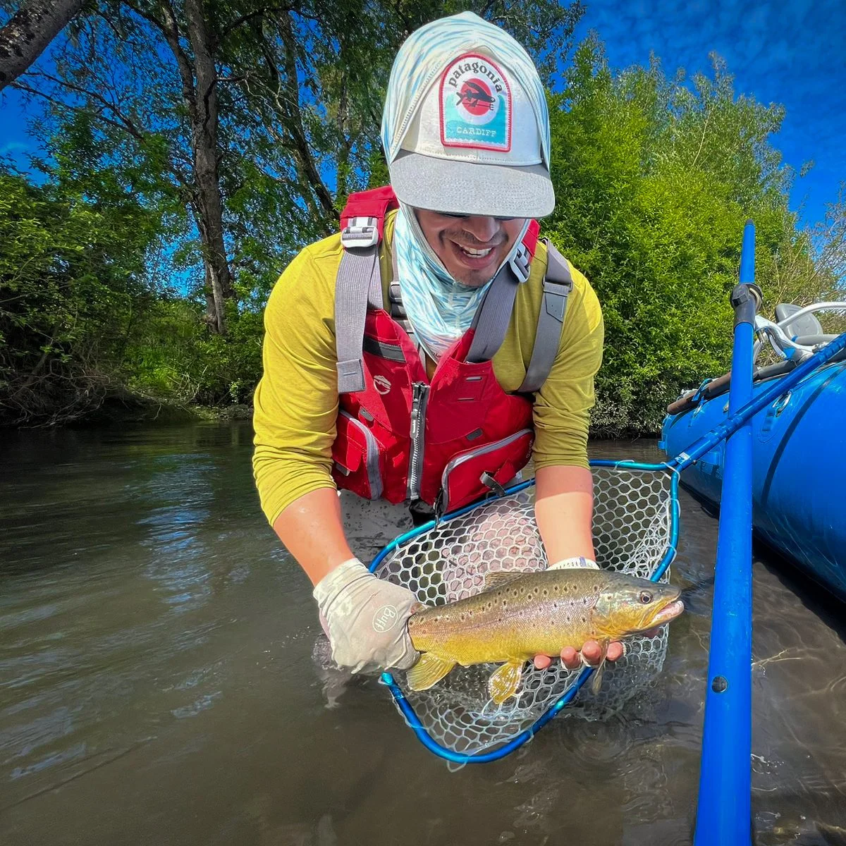 Angler releasing a wild trout from a raft during a sunny summer fly fishing float trip in Southern Chile.