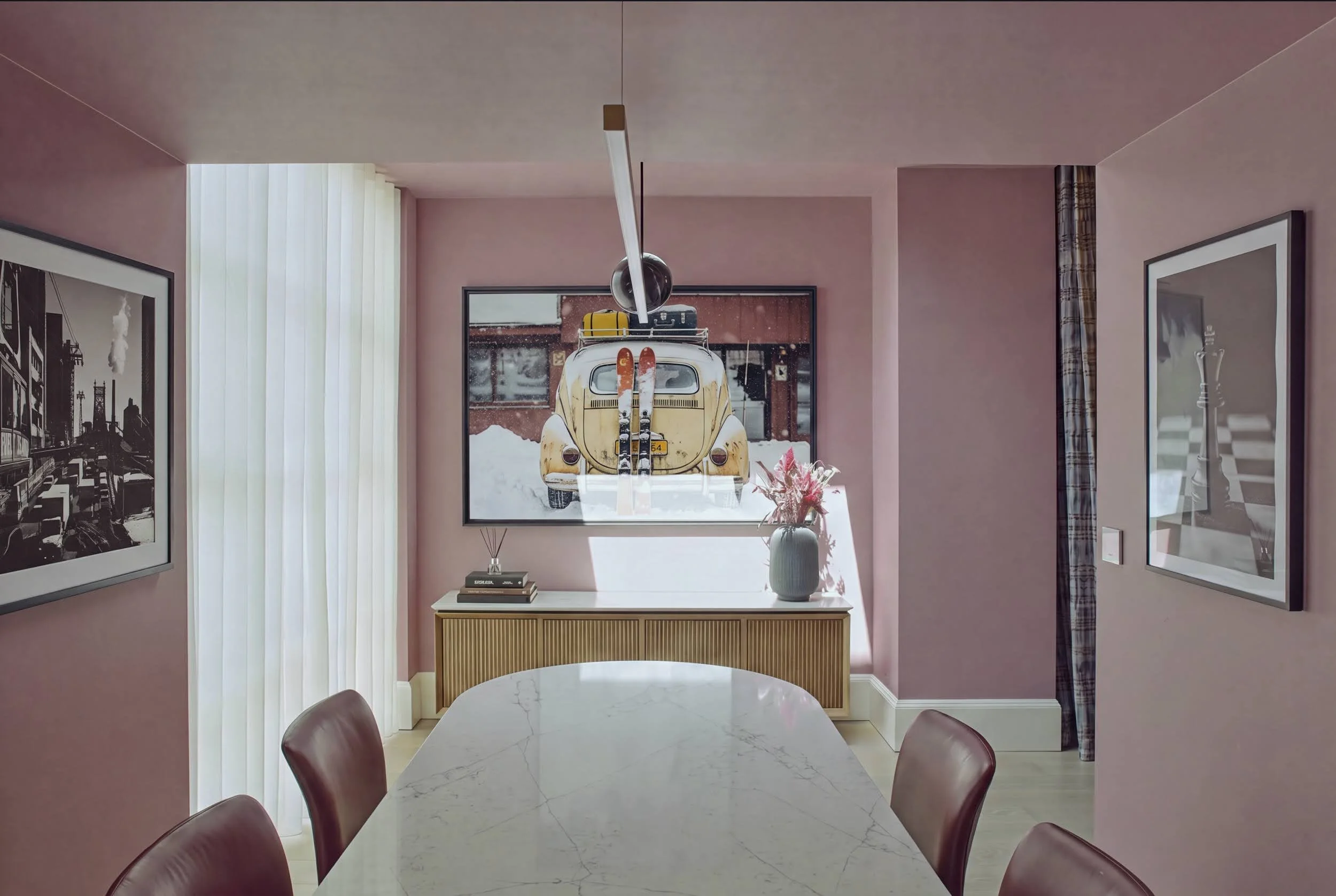 Pink dining room in Notting Hill with fluted oak sideboard, vintage ski photography print, sculptural pendant light and marble dining table