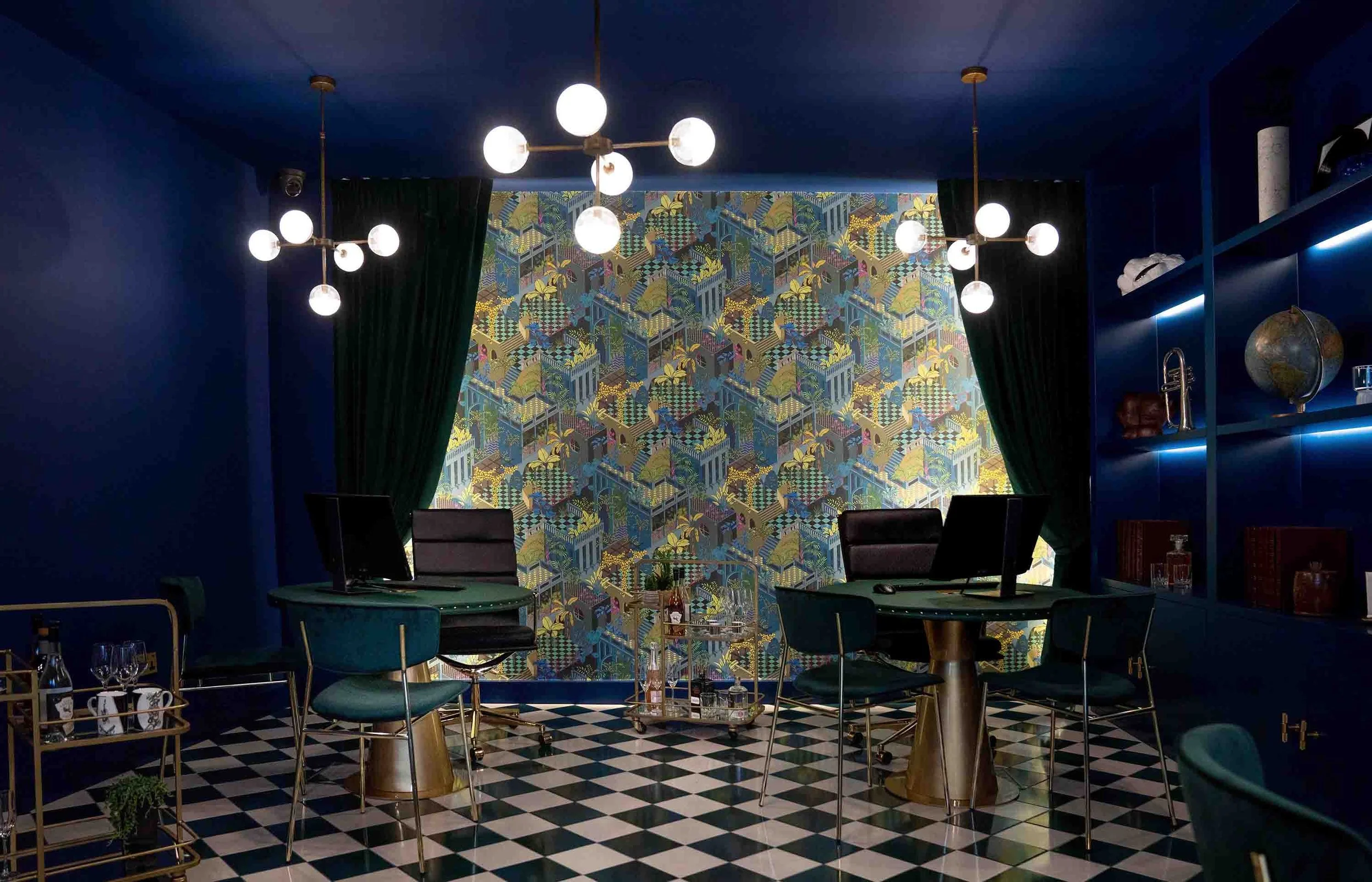 Open-plan office featuring rich blue ceilings, dramatic wallpaper from Cole&Son, round meeting tables for a members' club atmosphere.