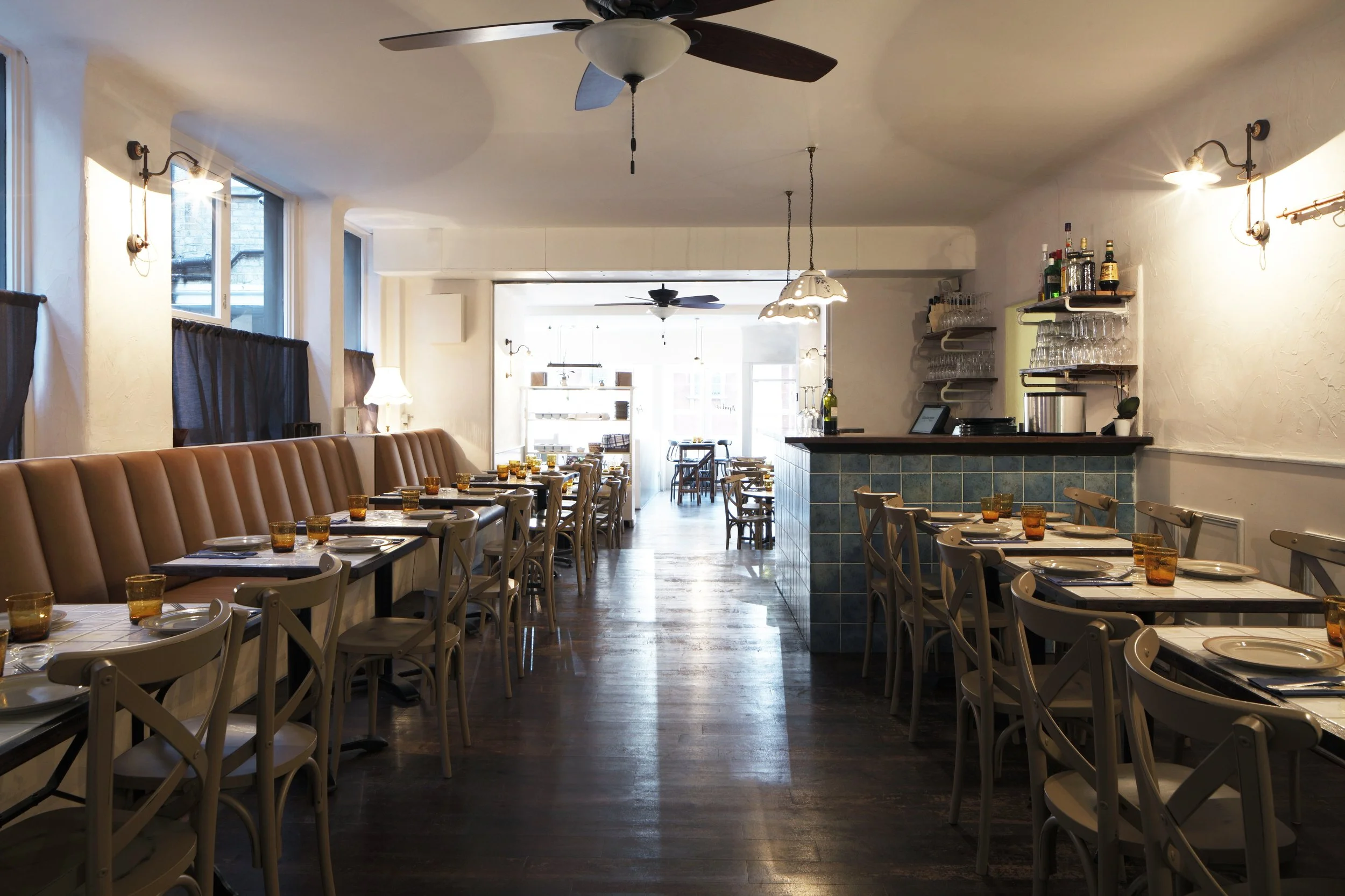 Interior of Apulia featuring vintage tables, banquettes, and warm lighting sourced from southern Italy