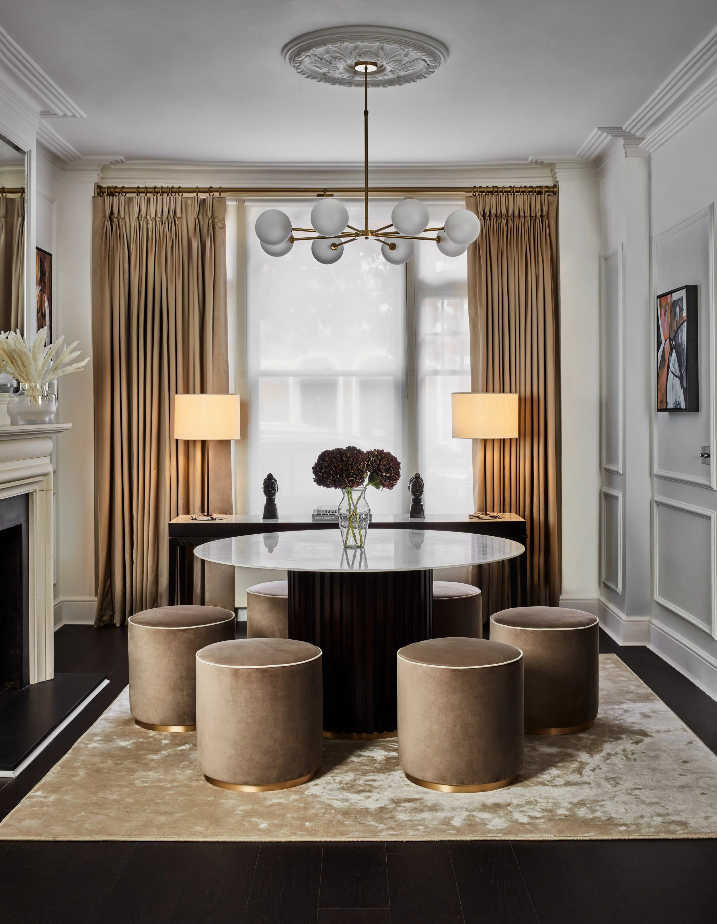 Residential entrance design with silk rug, round table with fluted dark oak strips and calacatta marble table, velvet poufs