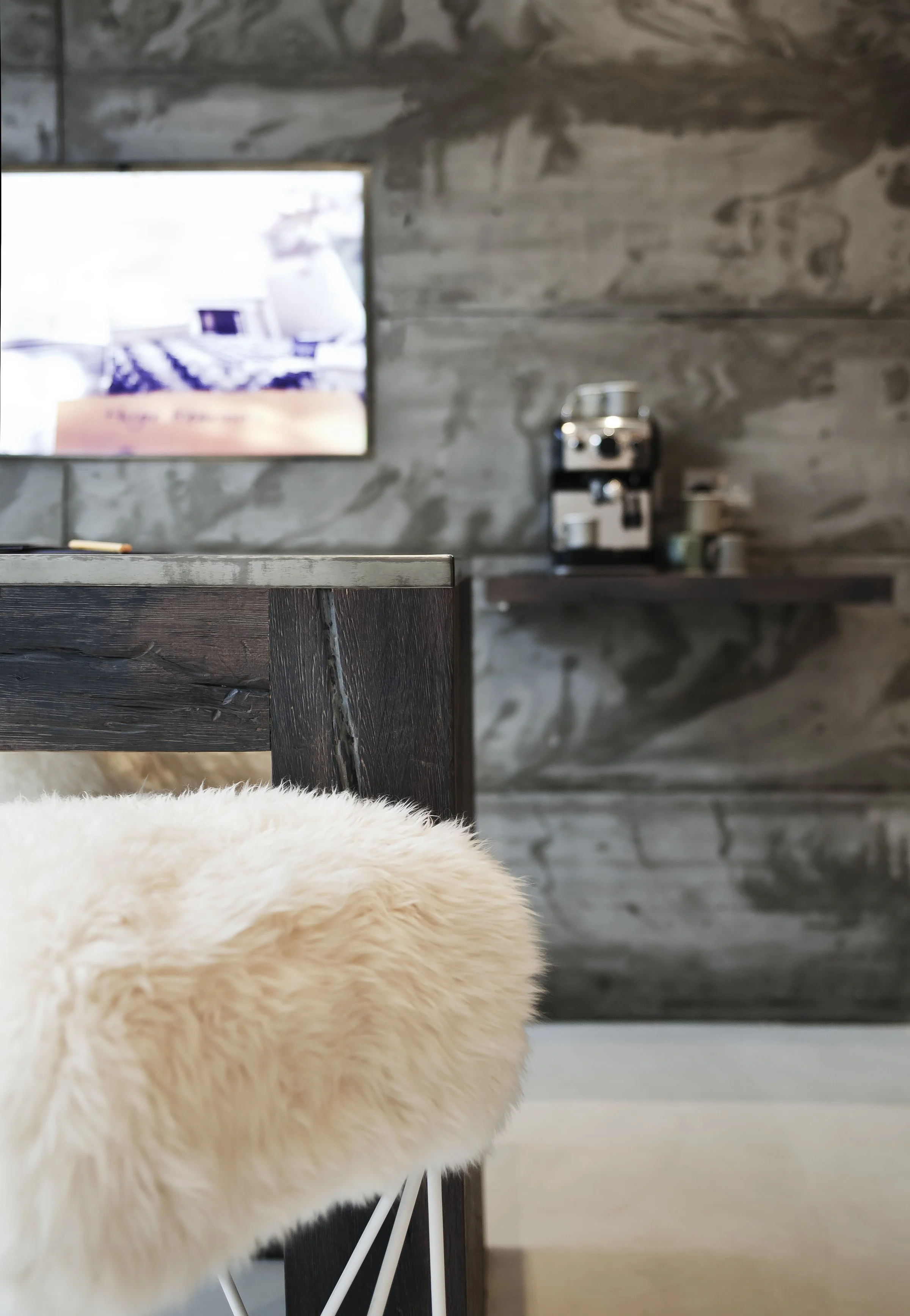 Close up of a chic contrast with sheepskin seating and concrete wall
