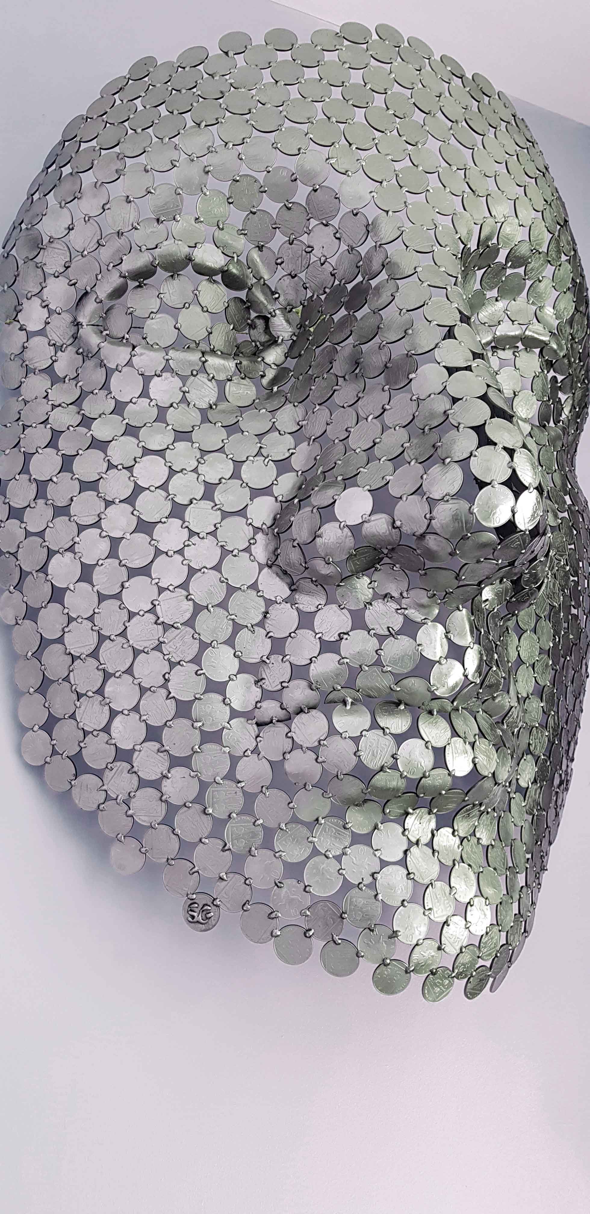 A magnificent face sculpture by Shaun Gagg crafted from 10p coins. This intricate piece captures striking facial features and texture, designed to hang elegantly on the wall,