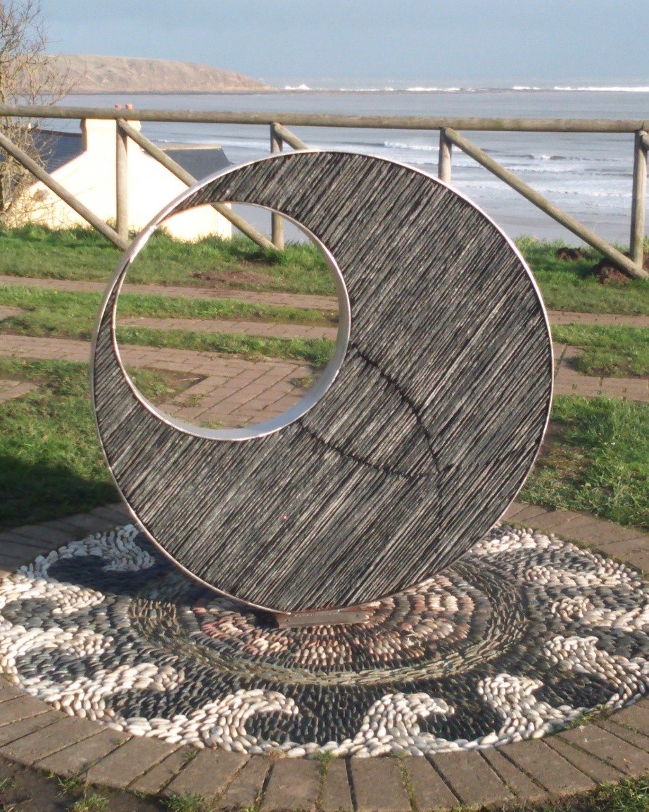Behold the mesmerizing beauty of Metamorphic Eclipse! 🌀 This captivating sculpture features two steel circles, symbolizing the infinite cycle of transformation. The inner circle, filled with stacked slate, begins the journey of a double helix, hinti