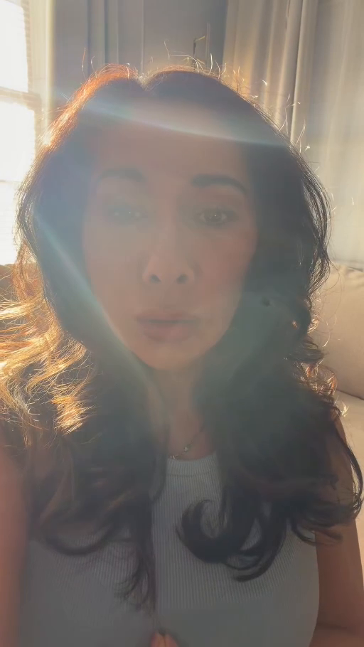 Stephanie seated in a gray top with sunlight, a blue light band across her forehead and a curved light pattern