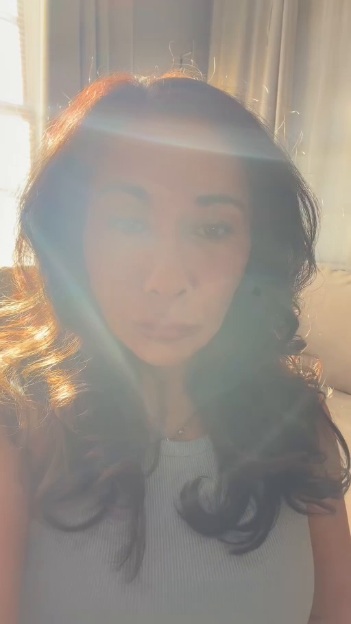 Stephanie beside a window with a blue-white light band across her forehead and soft light over the portrait