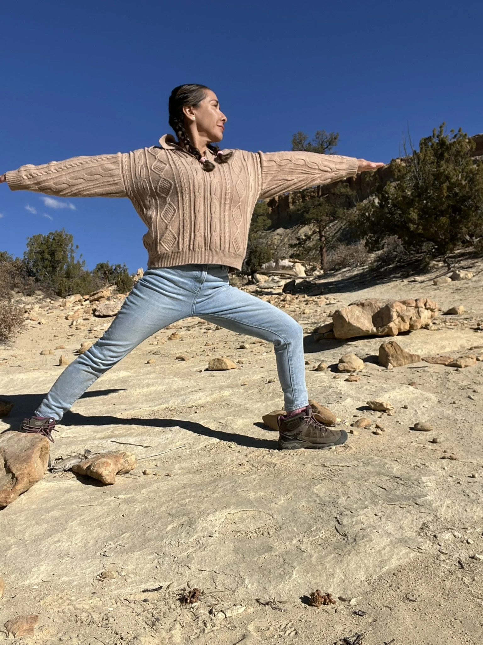 Stephanie practicing Warrior II in a mountain landscape