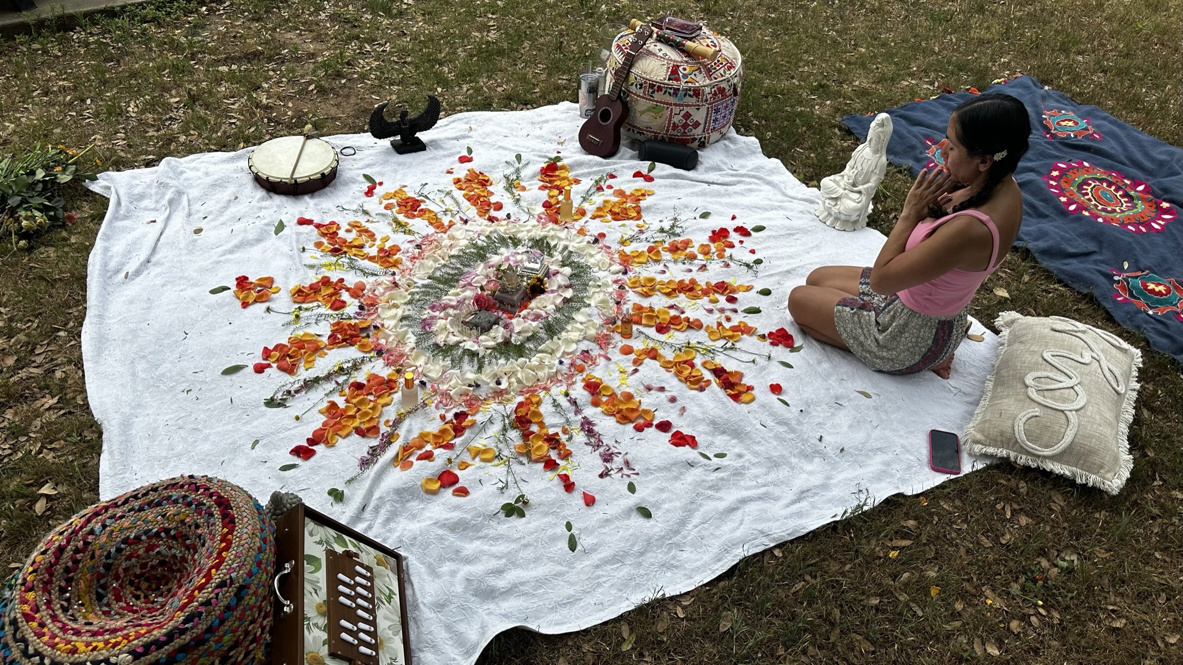 Stephanie beside a flower mandala in an outdoor sacred ritual space