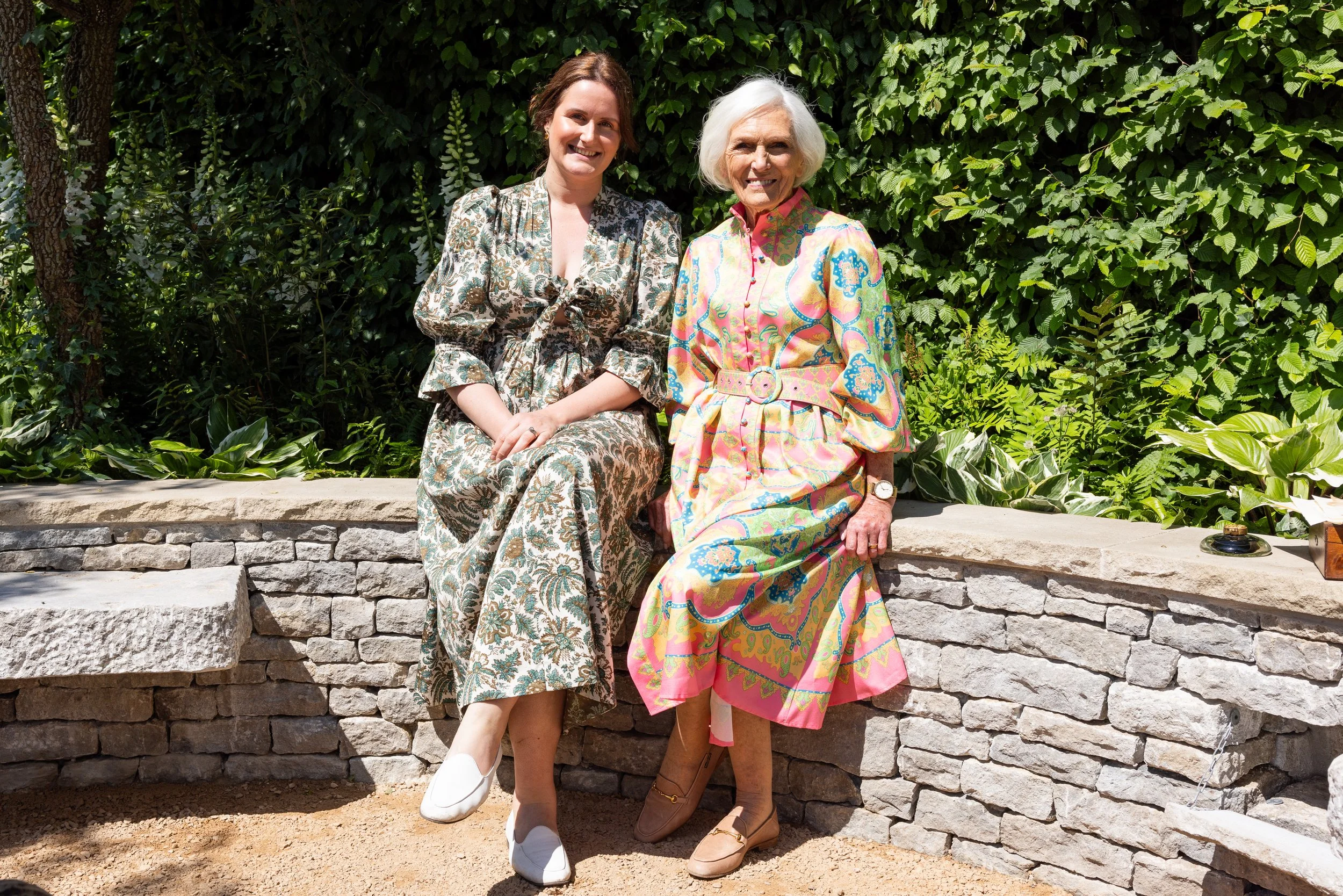 Designer Holly Johnston and Dame Mary Berry sit in the Bridgerton Garden during Press Day.