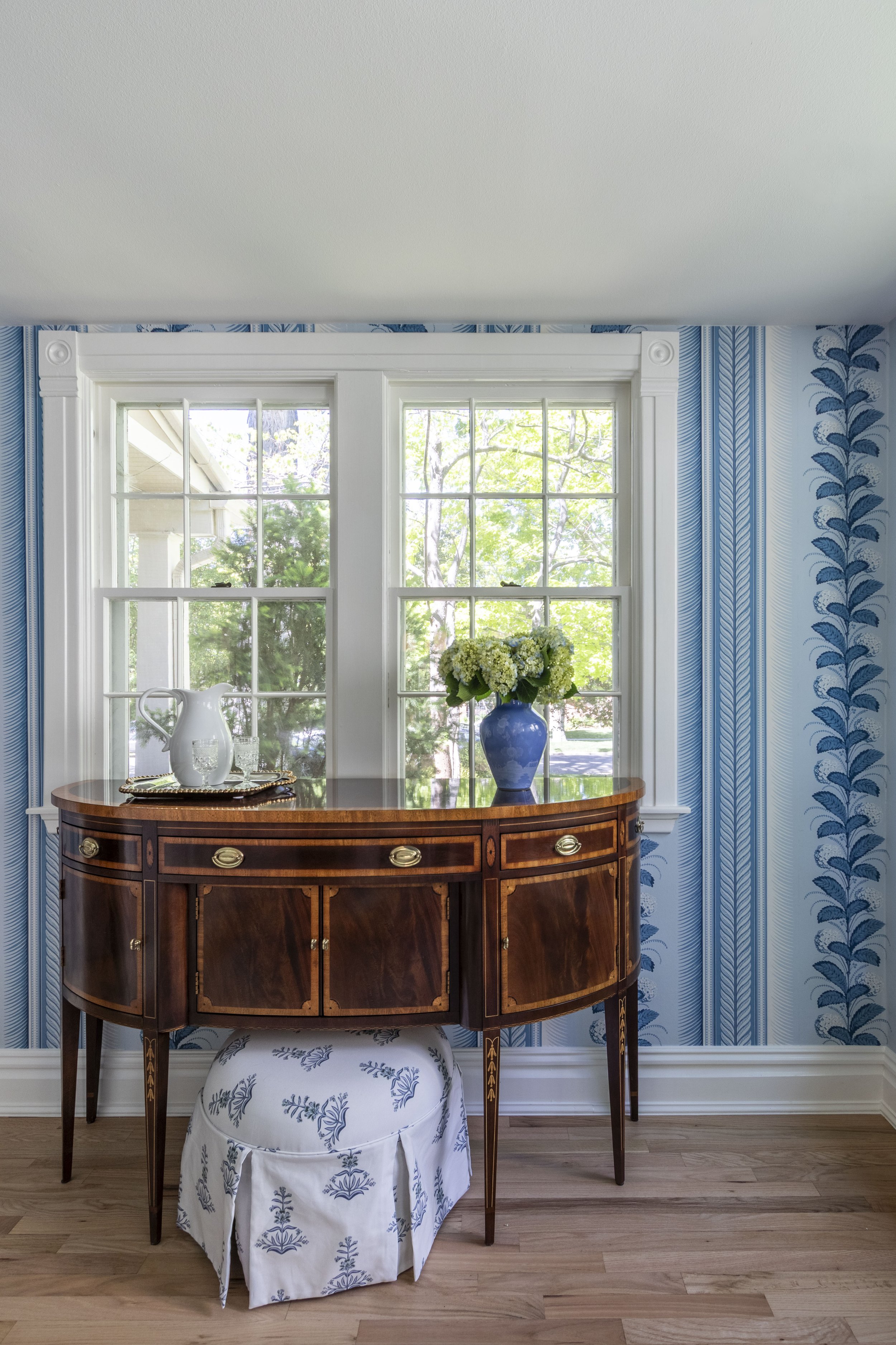 Transitional dining room design with fun blue wallpaper and a vintage buffet table