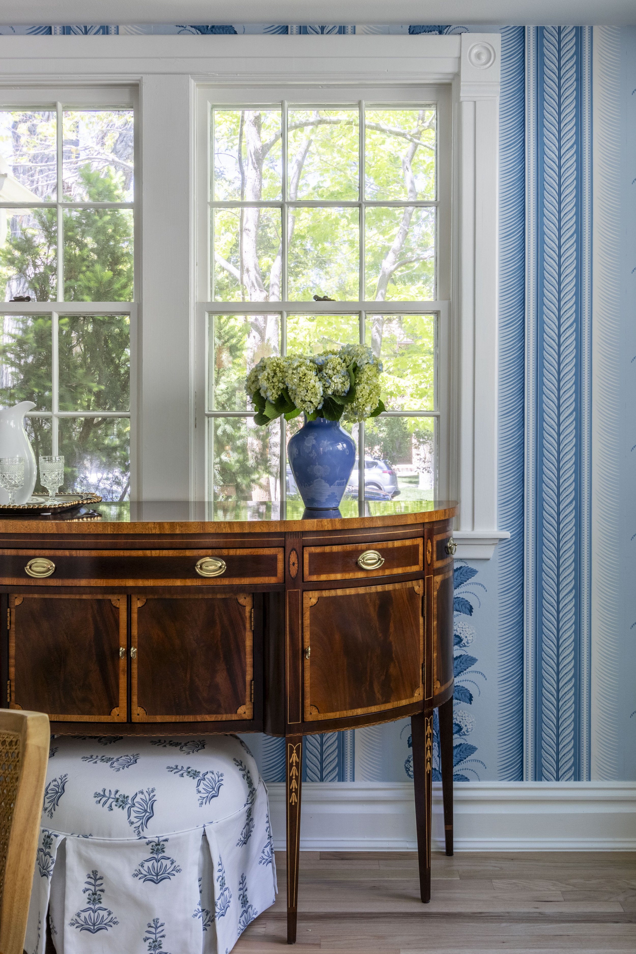 Transitional dining room design with fun blue wallpaper and a vintage buffet table