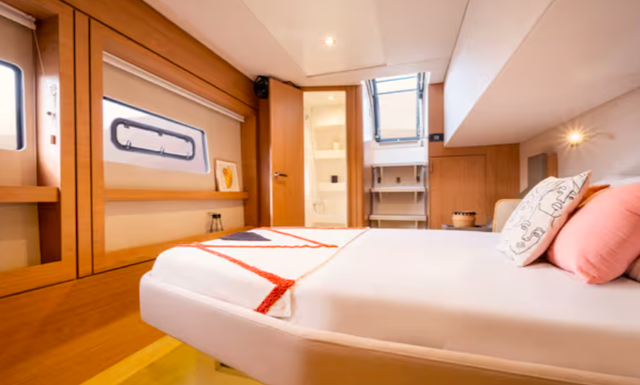 Interior of a modern yacht cabin with a bed and portholes.