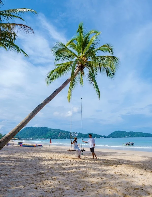 a-couple-of-men-and-women-on-a-swing-under-a-palm-2025-01-09-00-26-33-utc.jpg