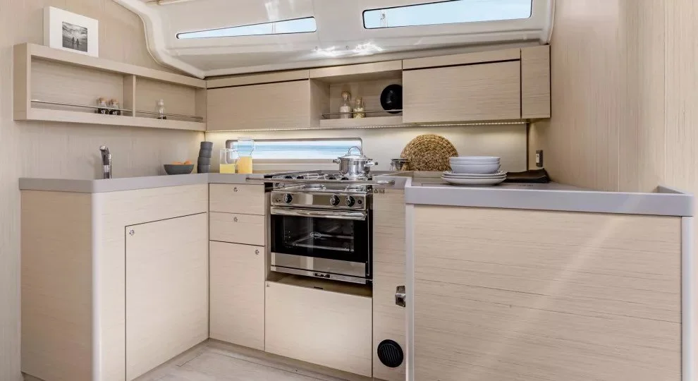 Modern yacht kitchen with light wood cabinetry, stainless steel stove, and minimalist decor.