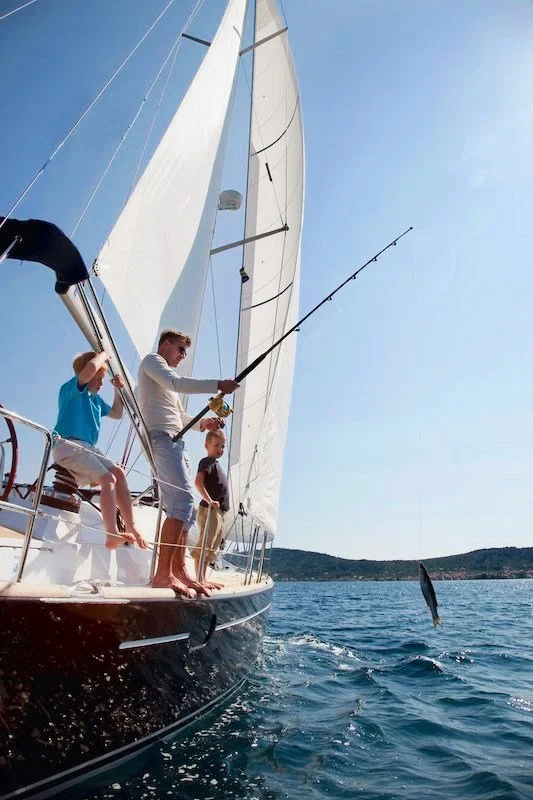 family fishing from sailing yacht