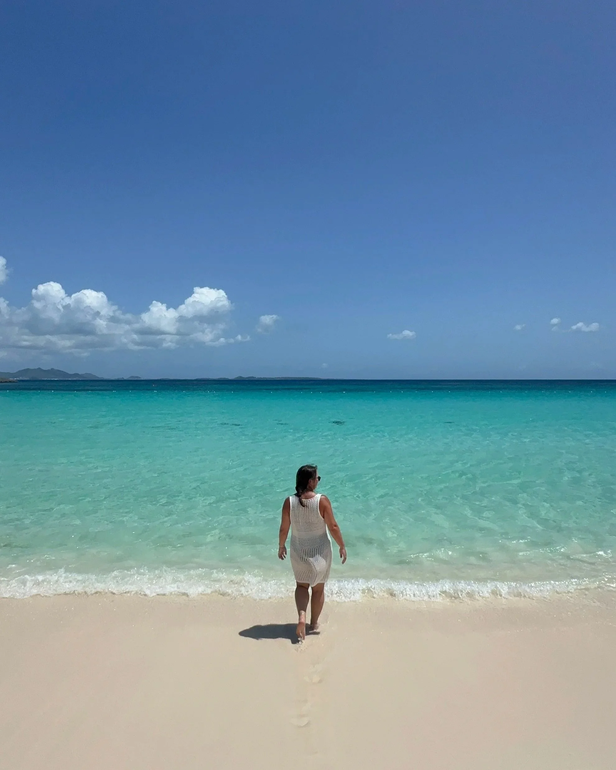 A girl walking into the water at Cap Julia, a Belmond Resort, in Anguilla.