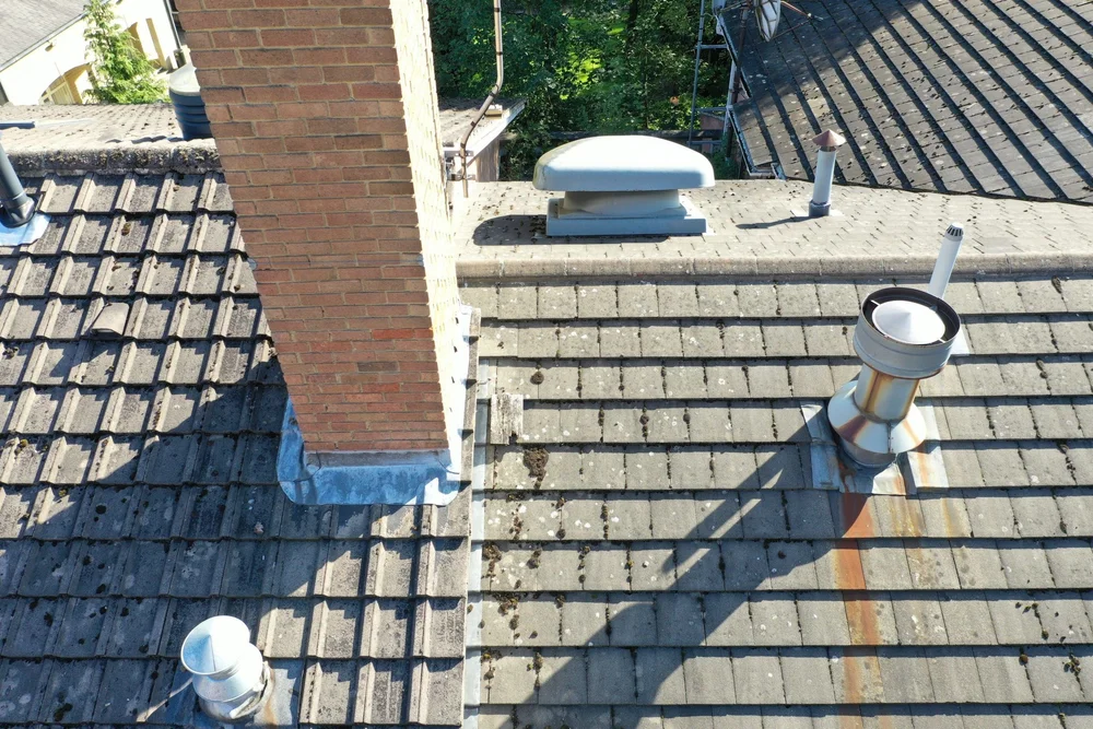 Aerial view of a tiled roof with a brick chimney and roof vents
