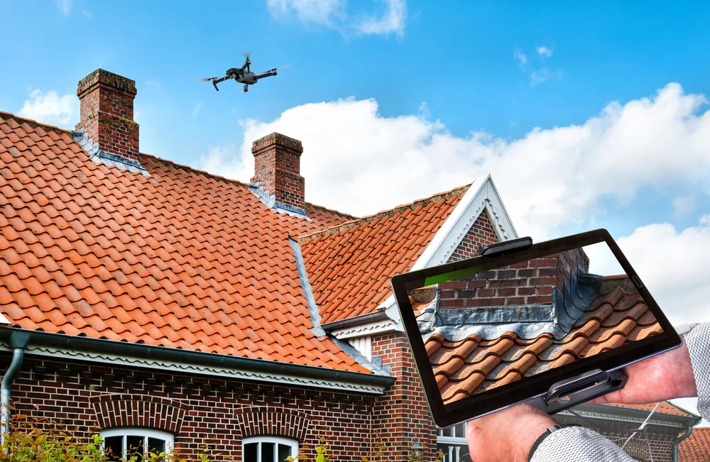 Illustration of a drone surveying a tiled roof with a tablet displaying roof details