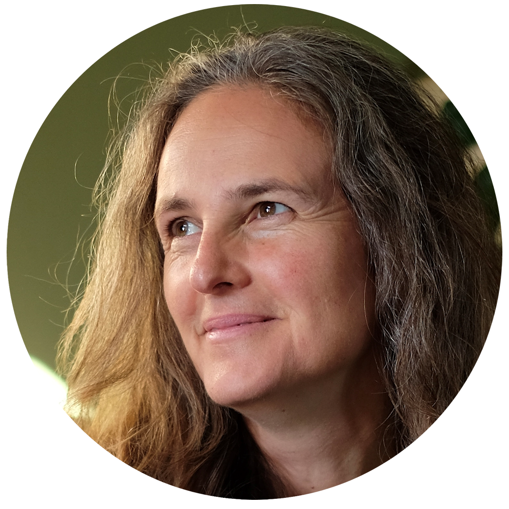 Close-up of a woman with long, curly brown hair smiling and looking to her left, with a light green background.