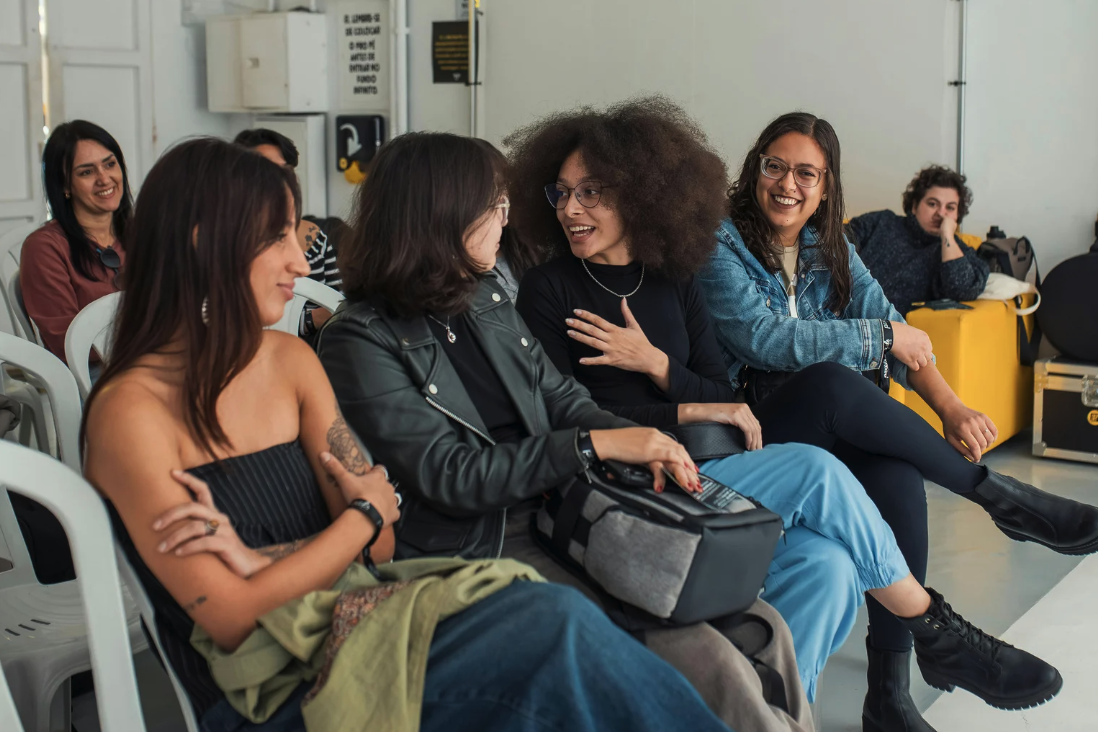 Group of diverse women seated and engaged in conversation in a casual setting.