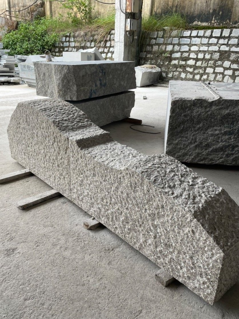 Large stone blocks in an industrial setting with a concrete floor and brick wall.