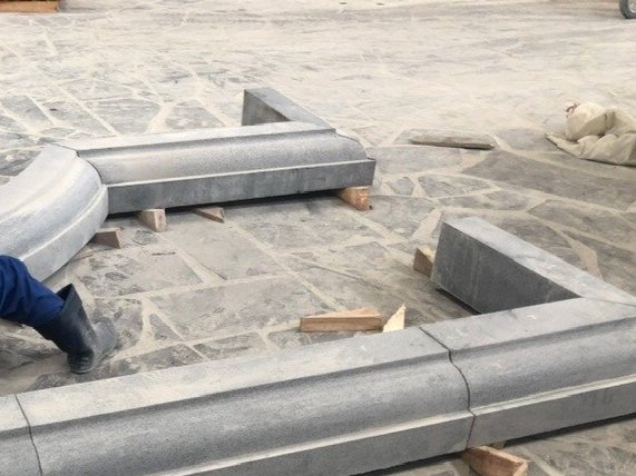 stone architectural elements with curved and angular shapes arranged on a stone-patterned floor
