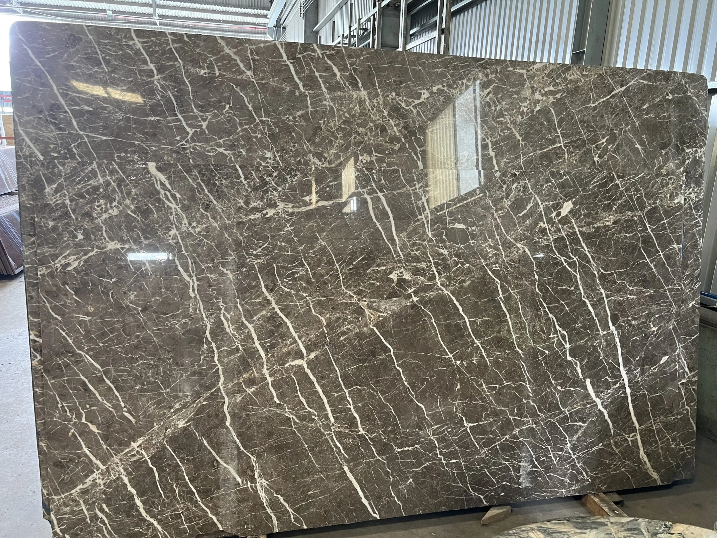 Large slab of brown marble with white veining, displayed indoors.