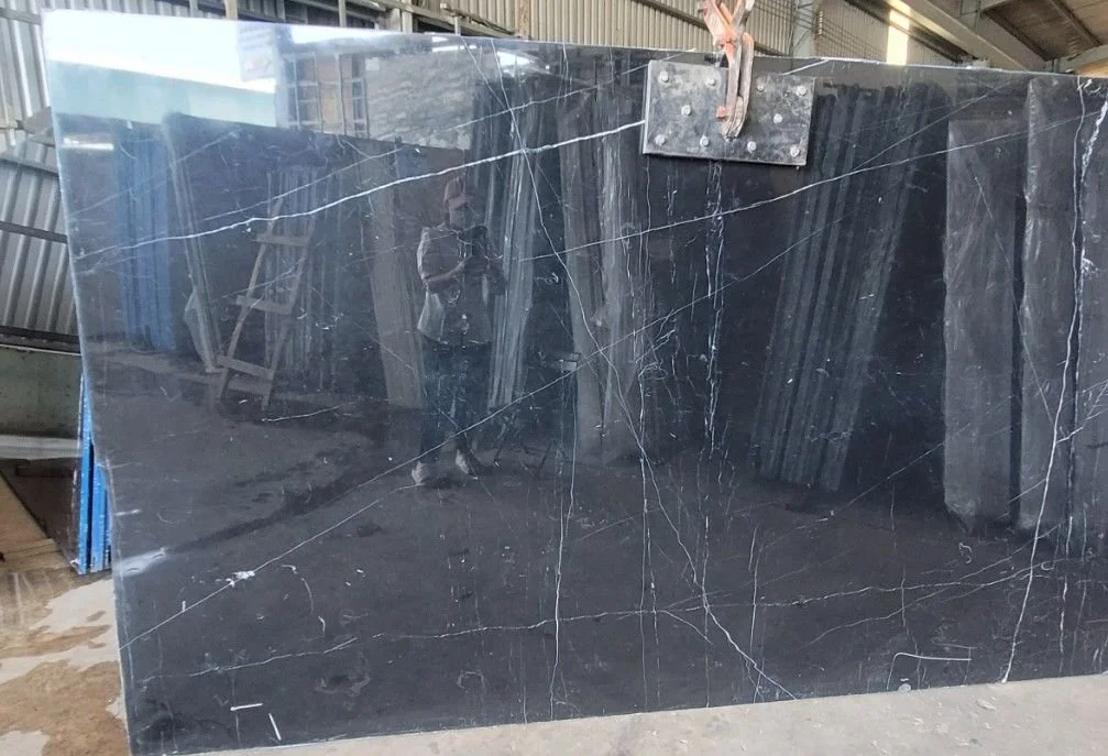 Large black marble slab with white veining in a warehouse