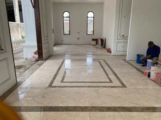 Interior room with marble floors and arched windows, man sitting on floor.